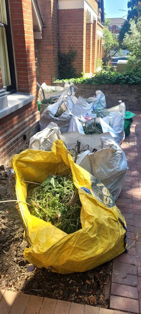 Bags of garden waste stacked by the front door ready to go in the van