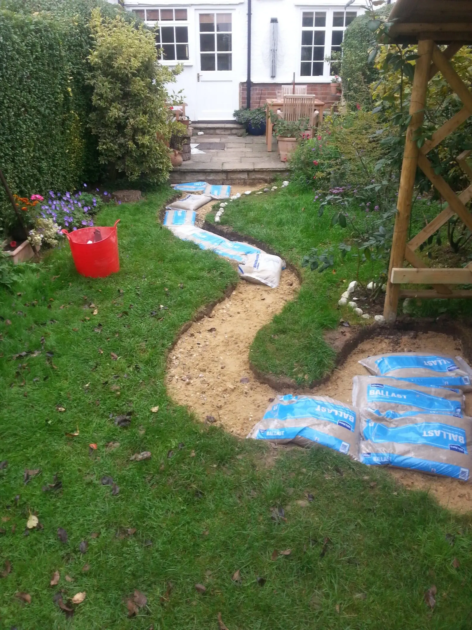Curved garden path being set out across a lawn, with bags of sand ready