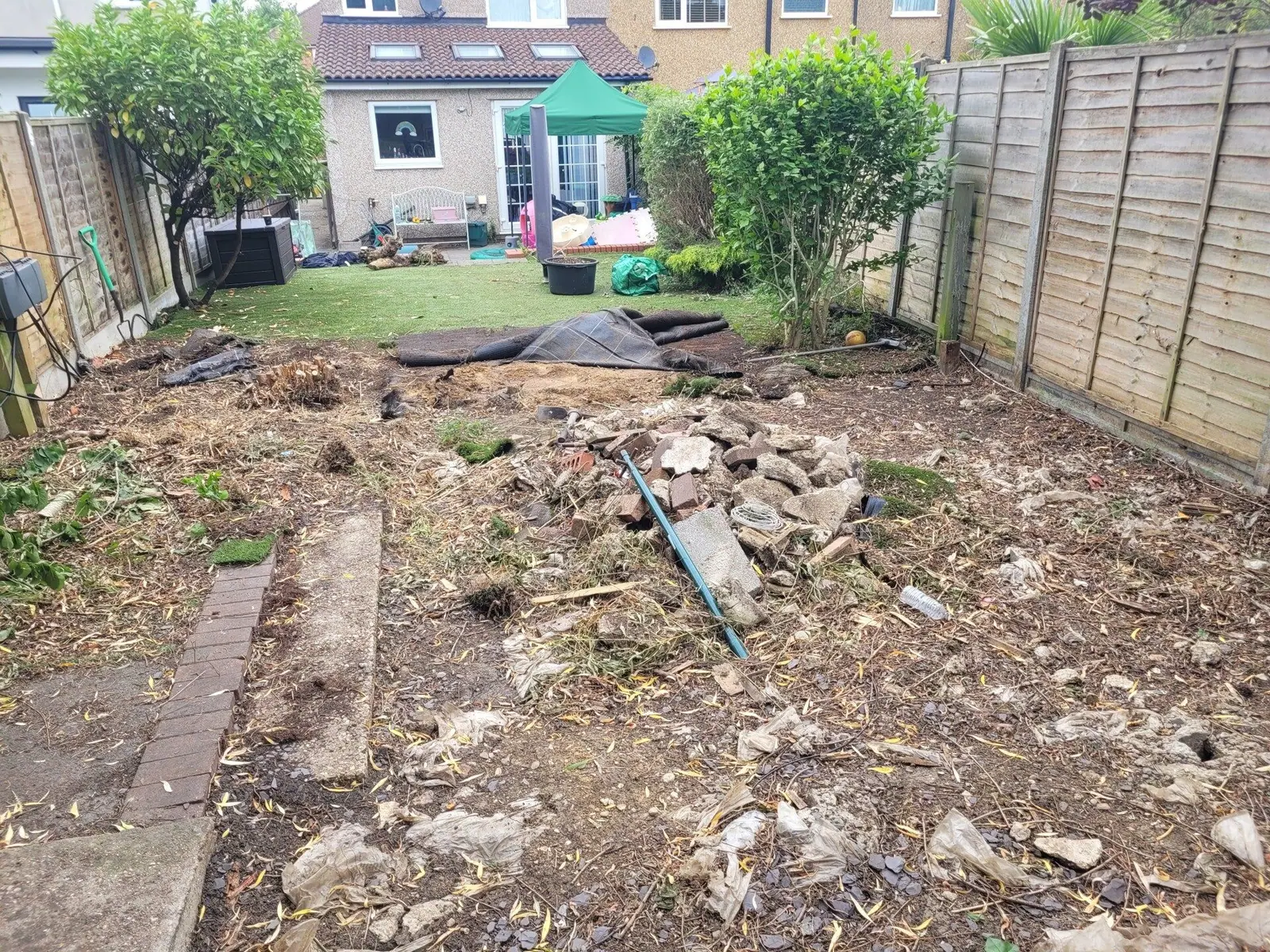Garden clearance in progress with old paving and debris being lifted