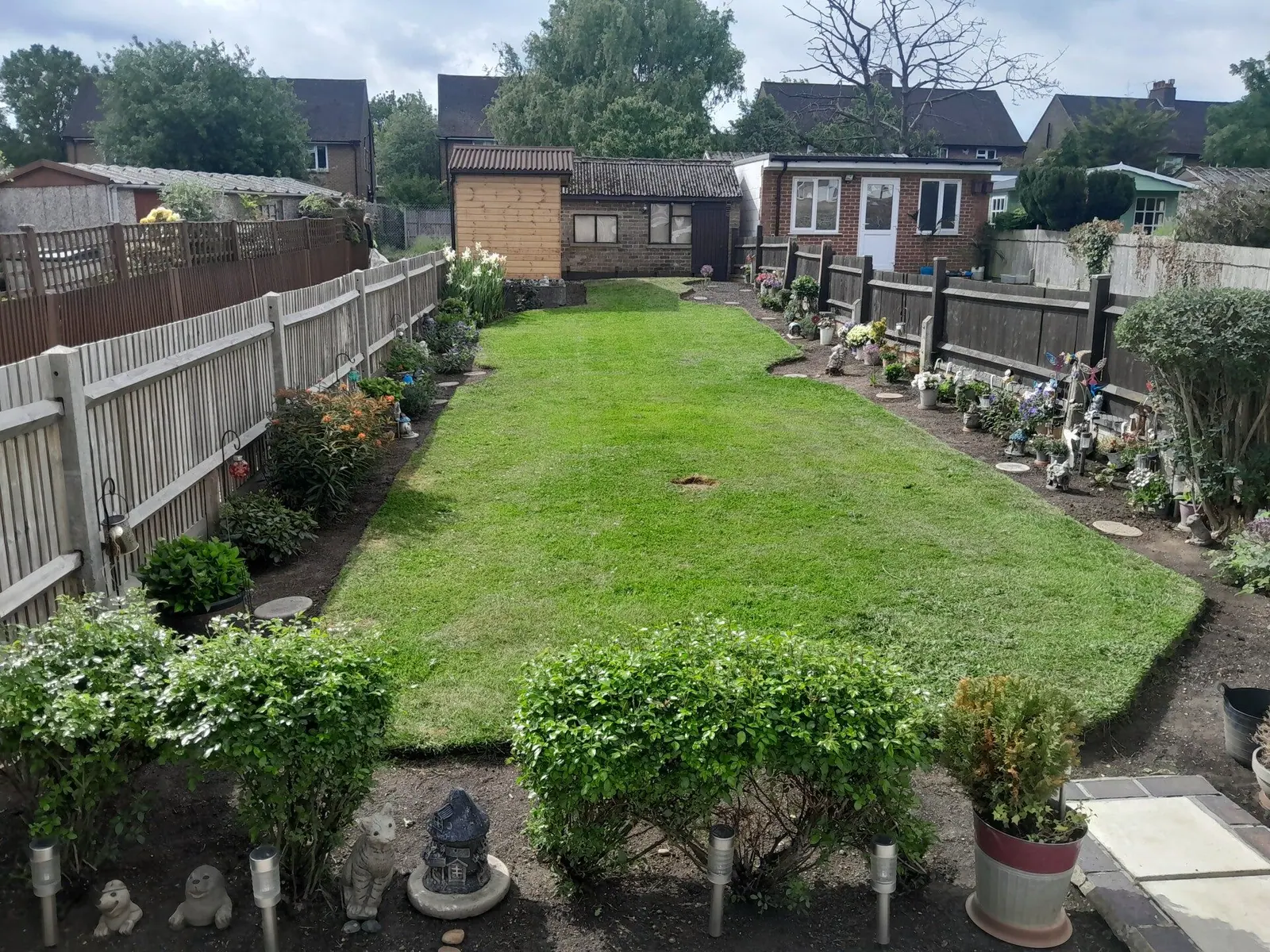 Long back-garden lawn freshly mowed and edged, with tidy borders either side