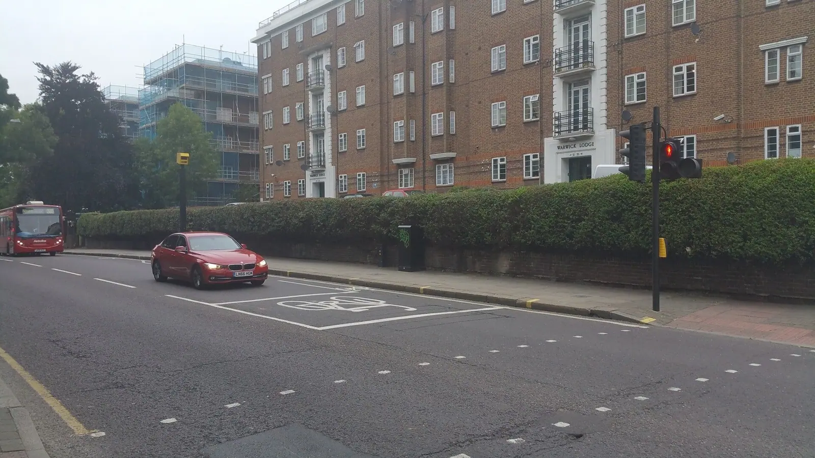 Long boundary hedge outside a block of flats trimmed level along the road