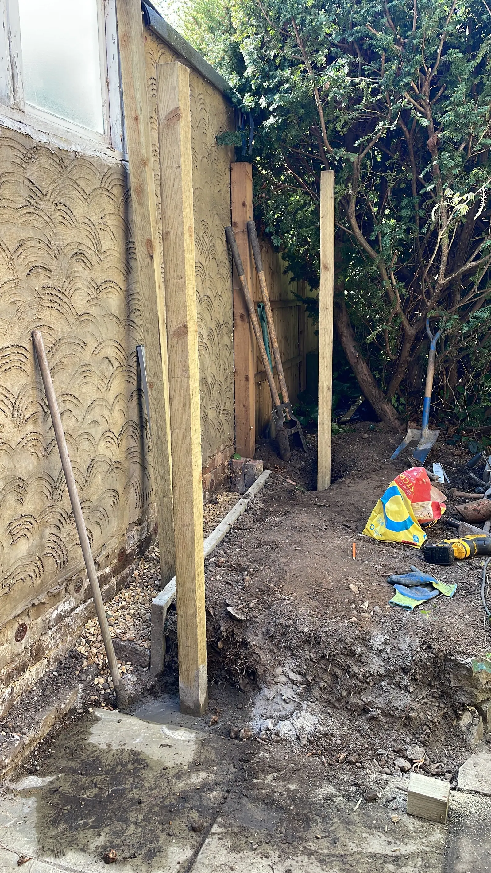 New timber fence posts set in concrete during a fence replacement