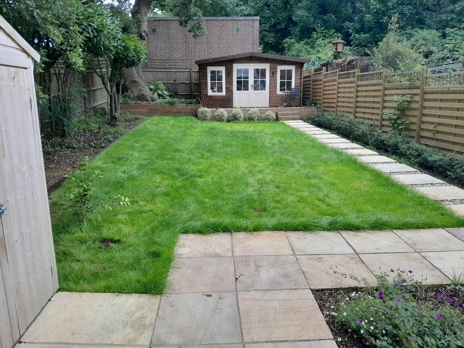 New turf lawn bedded in, with stepping stones and a summerhouse at the end of the garden